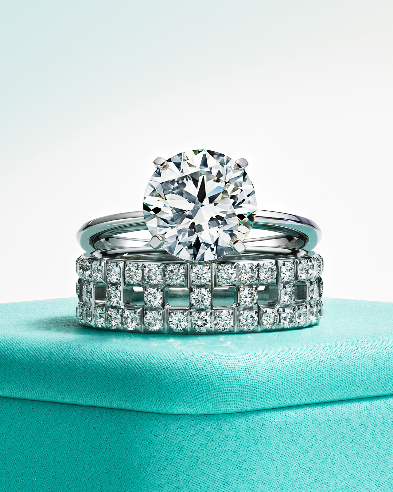 Photograph featuring an elegant engagement diamond ring stacked with a wedding band on top of a Anjeya box